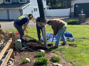 Three Washington Water employees excavating a service line for inspection in a residential area
