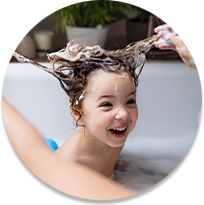 Child getting hair washed in bathtub