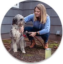 Woman washing dog with a hose